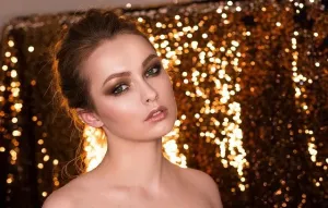 Zbliżenie oka, dłoń maluje precyzyjną jaskółkę czarnym eyelinerem, minimalistyczny, jasny makijaż dzienny.