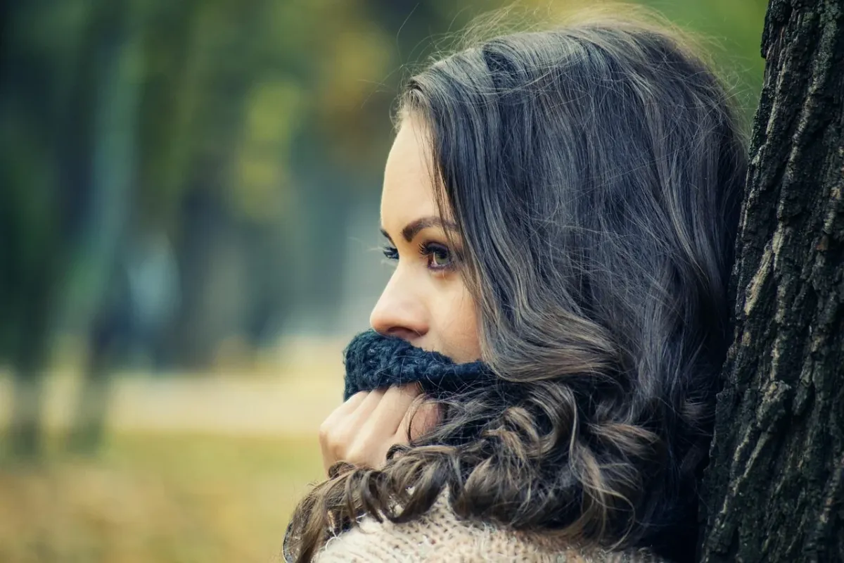 Portret brunetki w stylowym szaliku, prezentujący modną stylizację na chłodniejsze dni.